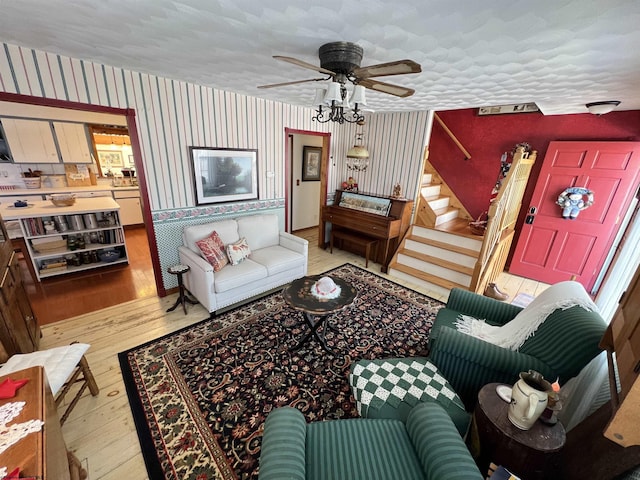 living room with light hardwood / wood-style floors, a textured ceiling, and ceiling fan