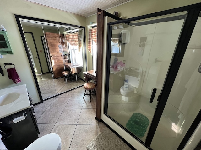 bathroom with an enclosed shower, vanity, toilet, and tile patterned flooring