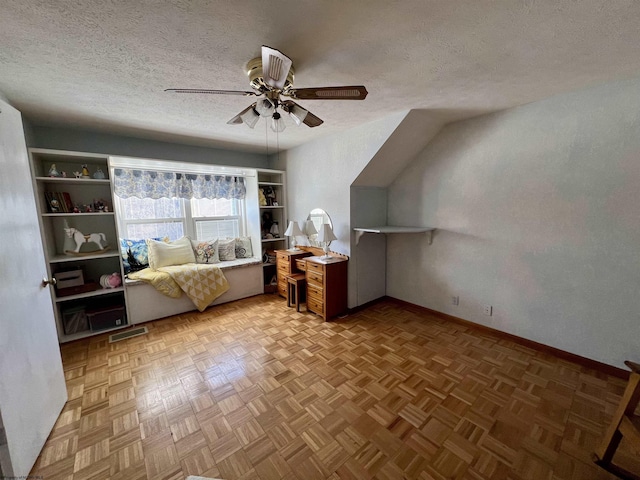 interior space with a textured ceiling, light parquet flooring, and ceiling fan