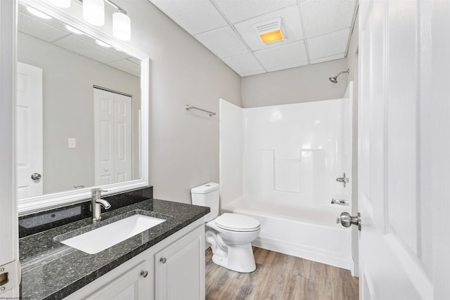 full bathroom with wood-type flooring, vanity, toilet, shower / bathtub combination, and a drop ceiling