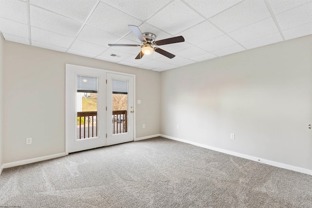 carpeted empty room with ceiling fan and a drop ceiling