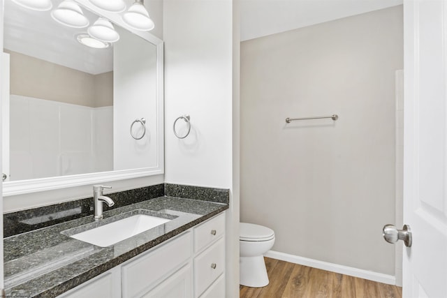 bathroom with hardwood / wood-style flooring, toilet, and vanity