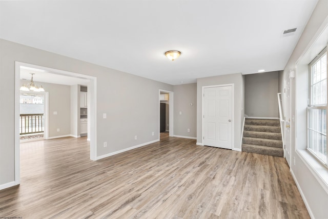 unfurnished room with a chandelier and light hardwood / wood-style floors