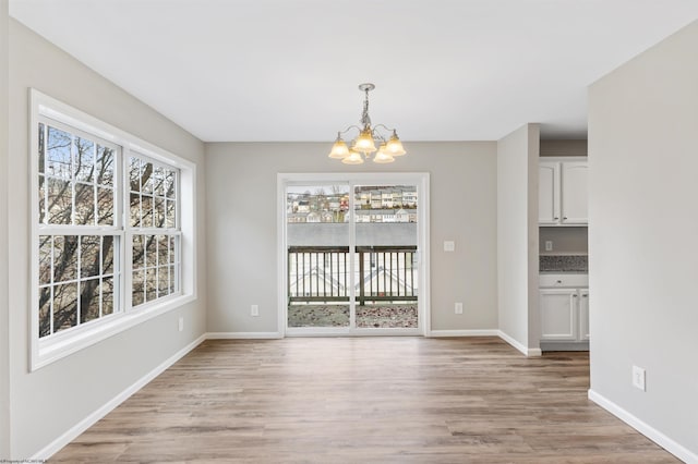 unfurnished dining area with a notable chandelier and light hardwood / wood-style floors