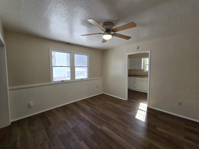 unfurnished bedroom featuring ceiling fan, dark hardwood / wood-style floors, and wooden walls