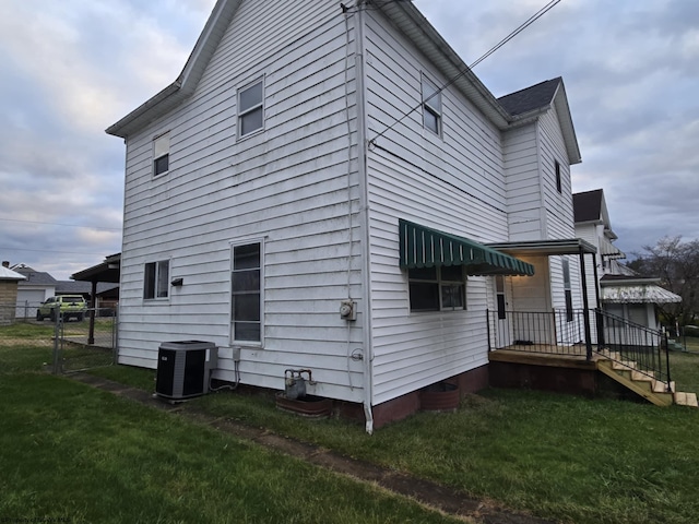 view of side of property with a lawn and cooling unit