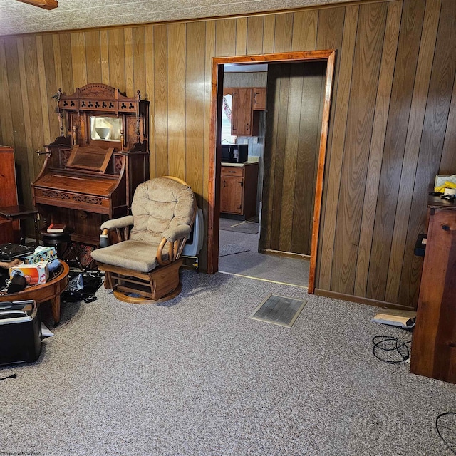 sitting room with dark carpet and wood walls