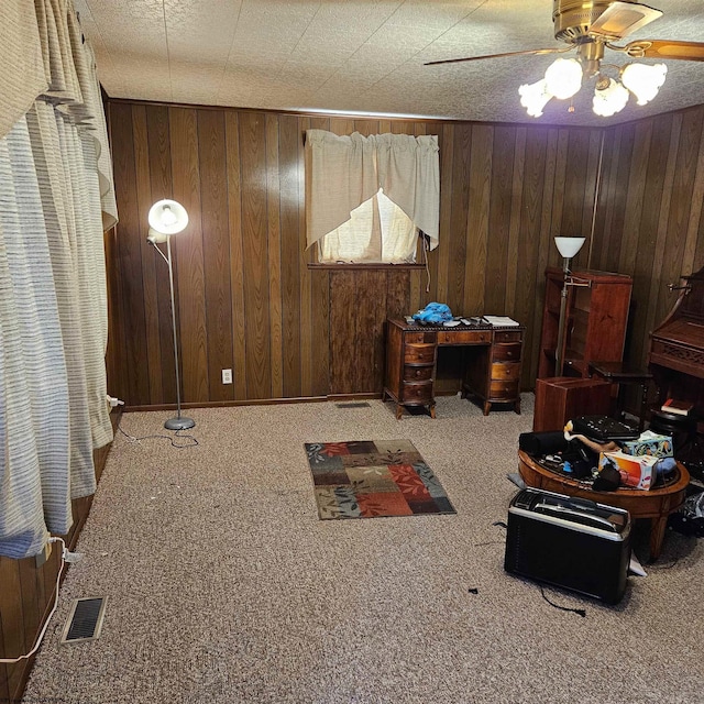 interior space with ceiling fan, carpet, and wood walls