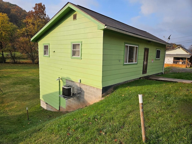 view of side of property featuring a lawn and central AC