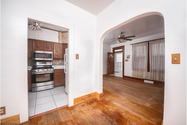 kitchen featuring light hardwood / wood-style floors, appliances with stainless steel finishes, ceiling fan, and decorative backsplash