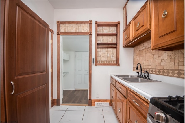 kitchen featuring sink, light tile patterned floors, backsplash, and stainless steel gas stove