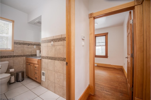 bathroom with tile walls, tile patterned floors, and toilet