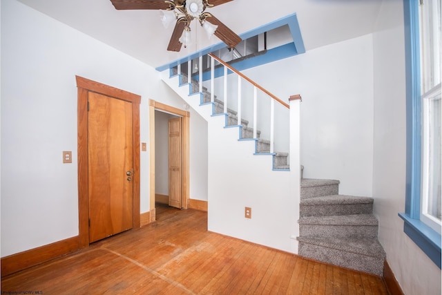 stairs featuring hardwood / wood-style flooring and ceiling fan