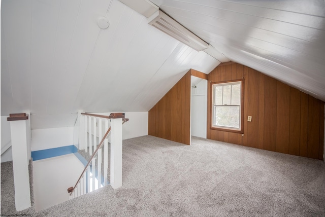 bonus room featuring vaulted ceiling, wood walls, and carpet flooring