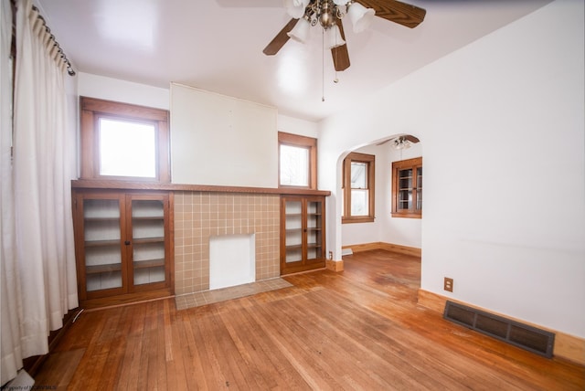 unfurnished living room featuring ceiling fan, hardwood / wood-style floors, and a tile fireplace