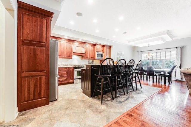 kitchen with appliances with stainless steel finishes, custom exhaust hood, a center island, a kitchen breakfast bar, and decorative light fixtures