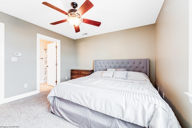 carpeted bedroom with ensuite bathroom and ceiling fan