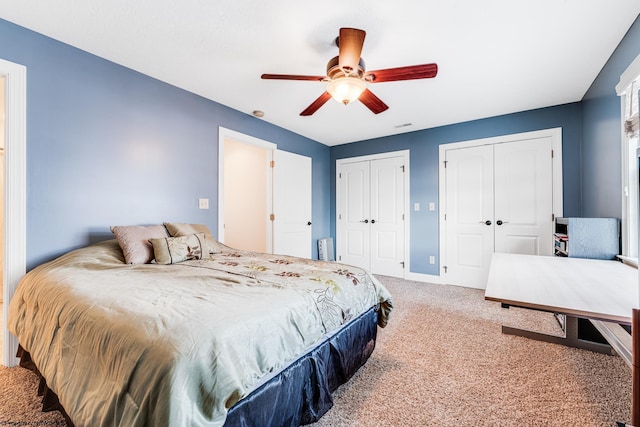 bedroom with carpet flooring, ceiling fan, and multiple closets