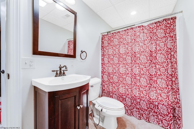 bathroom with toilet, a shower with curtain, a drop ceiling, tile patterned floors, and vanity