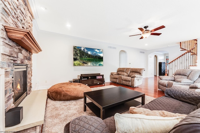 living room with a fireplace, light hardwood / wood-style flooring, crown molding, and ceiling fan