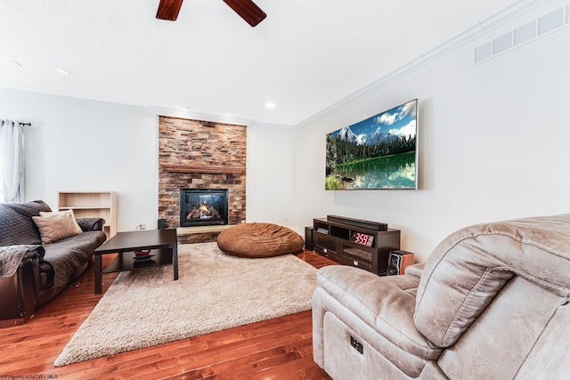 living room featuring a fireplace, hardwood / wood-style floors, crown molding, and ceiling fan