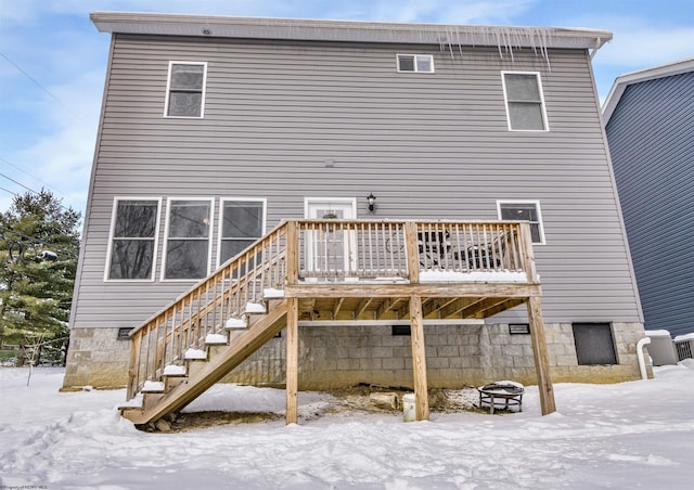 snow covered house with a deck and a fire pit