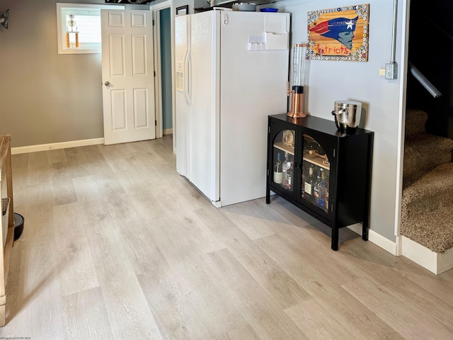 basement featuring white fridge with ice dispenser and light wood-type flooring