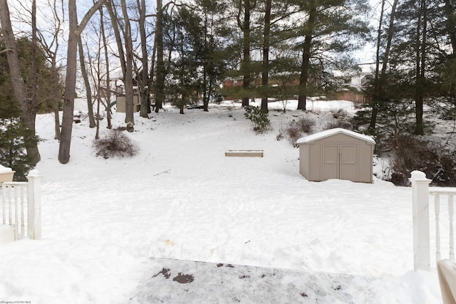 yard layered in snow featuring a storage unit