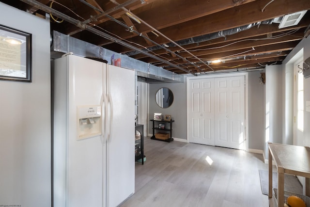 basement featuring white refrigerator with ice dispenser and light wood-type flooring