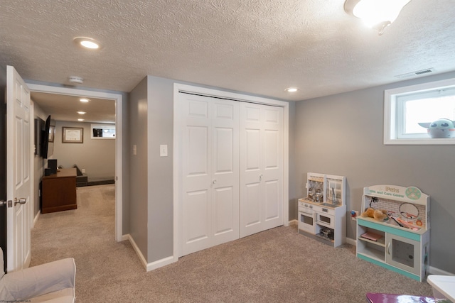 recreation room featuring light carpet and a textured ceiling