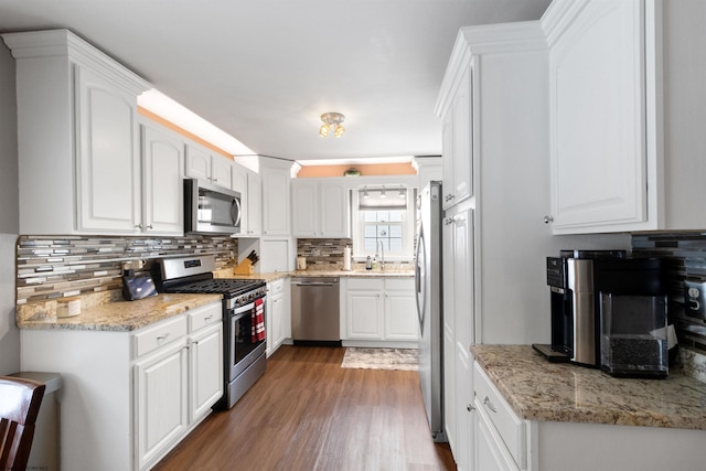 kitchen with white cabinetry, appliances with stainless steel finishes, dark hardwood / wood-style floors, and light stone counters