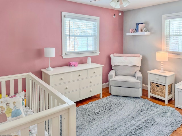 bedroom featuring light hardwood / wood-style flooring, a nursery area, and ceiling fan