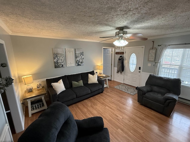 living room featuring ornamental molding, wood-type flooring, ceiling fan, and a textured ceiling