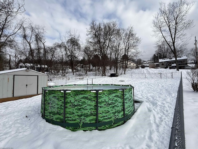 snowy yard featuring a storage shed