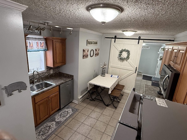 kitchen with light tile patterned flooring, sink, crown molding, appliances with stainless steel finishes, and a barn door