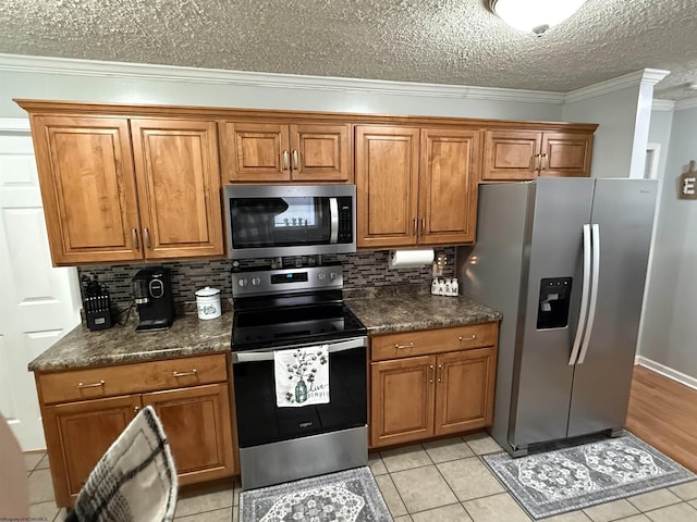 kitchen featuring crown molding, a textured ceiling, light tile patterned floors, appliances with stainless steel finishes, and decorative backsplash