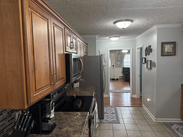 kitchen featuring range with electric cooktop, dark stone countertops, ornamental molding, and light tile patterned floors