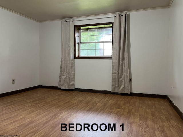 empty room featuring hardwood / wood-style flooring and crown molding