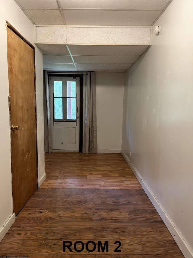 hallway featuring dark wood-type flooring and a drop ceiling