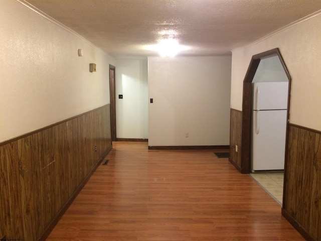 hall with crown molding, light hardwood / wood-style flooring, and a textured ceiling