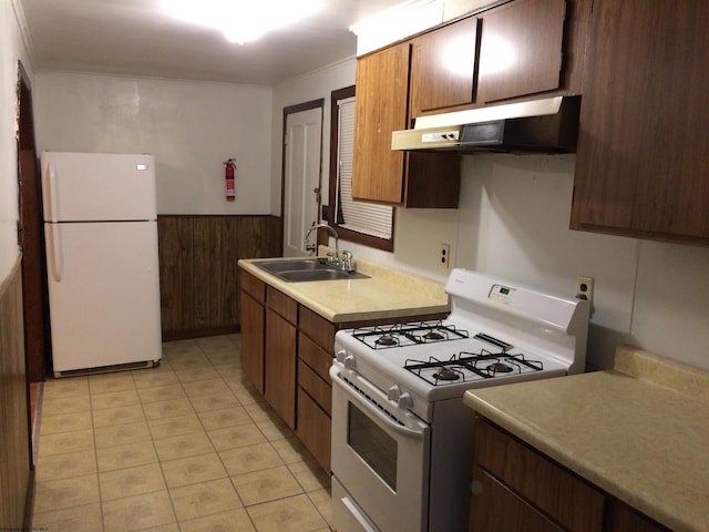 kitchen featuring sink, crown molding, white appliances, wooden walls, and light tile patterned flooring