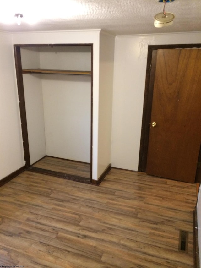 unfurnished bedroom with dark wood-type flooring, a closet, and a textured ceiling