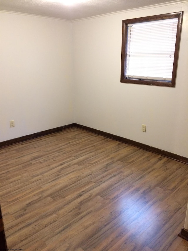 spare room with crown molding and dark hardwood / wood-style floors