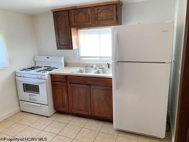 kitchen featuring white appliances, sink, and light tile patterned floors