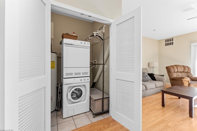 laundry room featuring light tile patterned floors, gas water heater, and stacked washer and clothes dryer