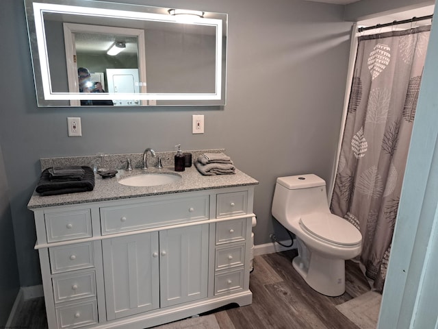 full bathroom featuring toilet, curtained shower, wood finished floors, baseboards, and vanity