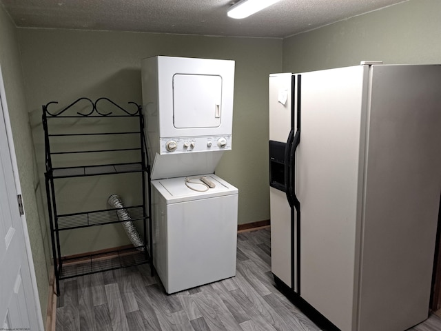 laundry room with light wood-type flooring, a textured ceiling, stacked washing maching and dryer, baseboards, and laundry area