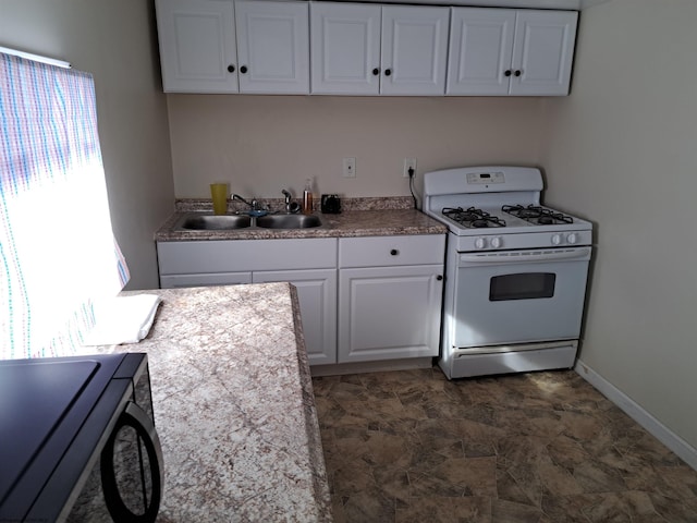 kitchen with white cabinets, white gas stove, and a sink