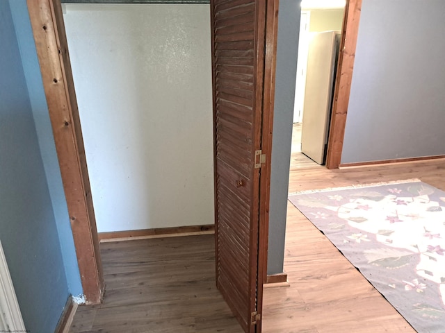 corridor with baseboards and wood finished floors