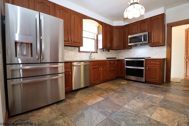 kitchen with sink, decorative backsplash, light stone countertops, and appliances with stainless steel finishes